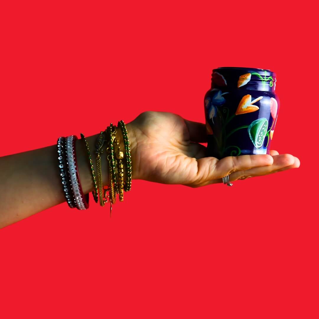 red background with hand holding a jar, the hand is wearing jewellery