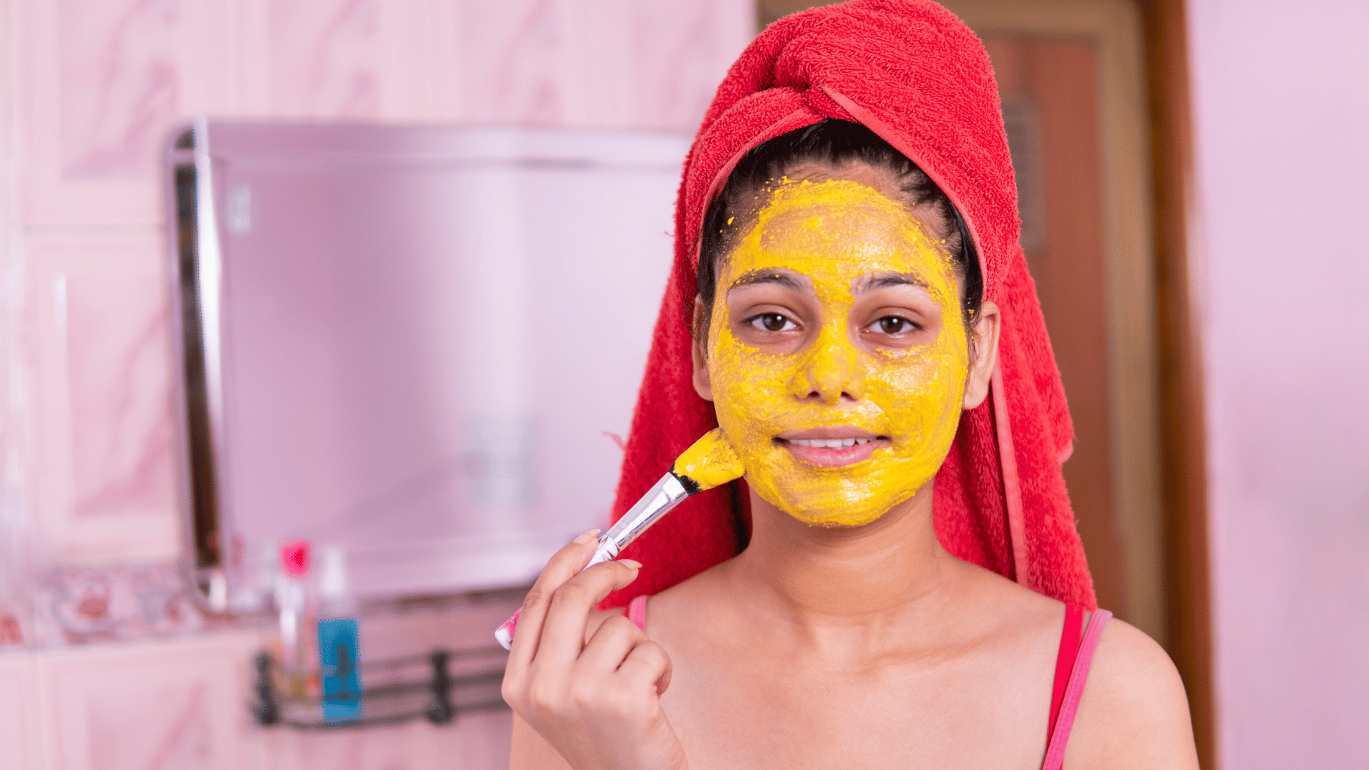 a young woman applying turmeric face mask