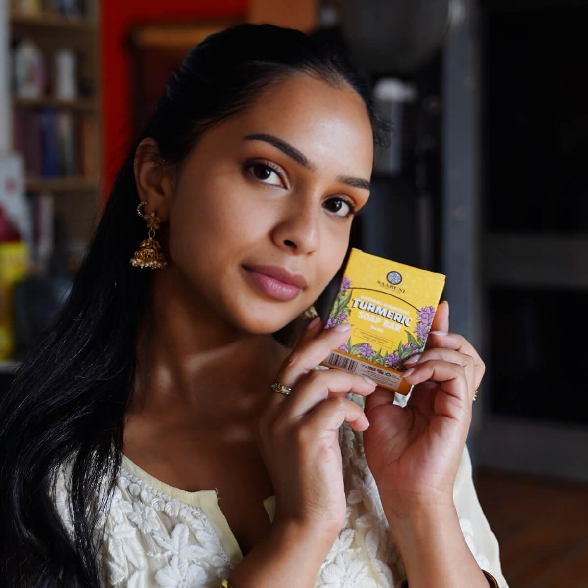 A South Asian woman holding up a soap bar