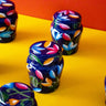 Decorative jars with floral patterns on a yellow surface against an orange wall.