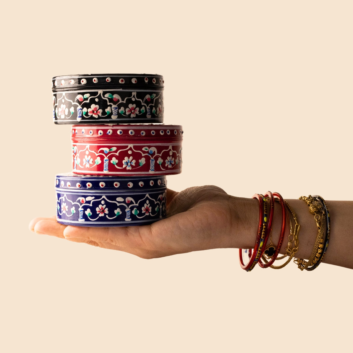 woman holds three colourful tin jars of cream