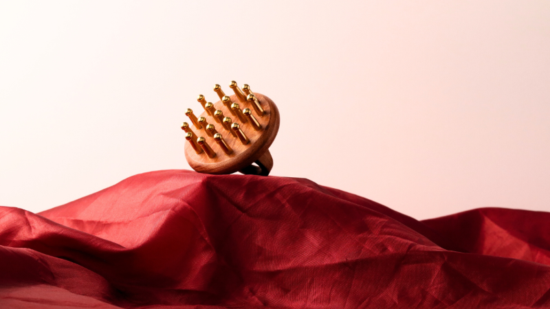 Wooden hair massager on a red fabric with a pink background