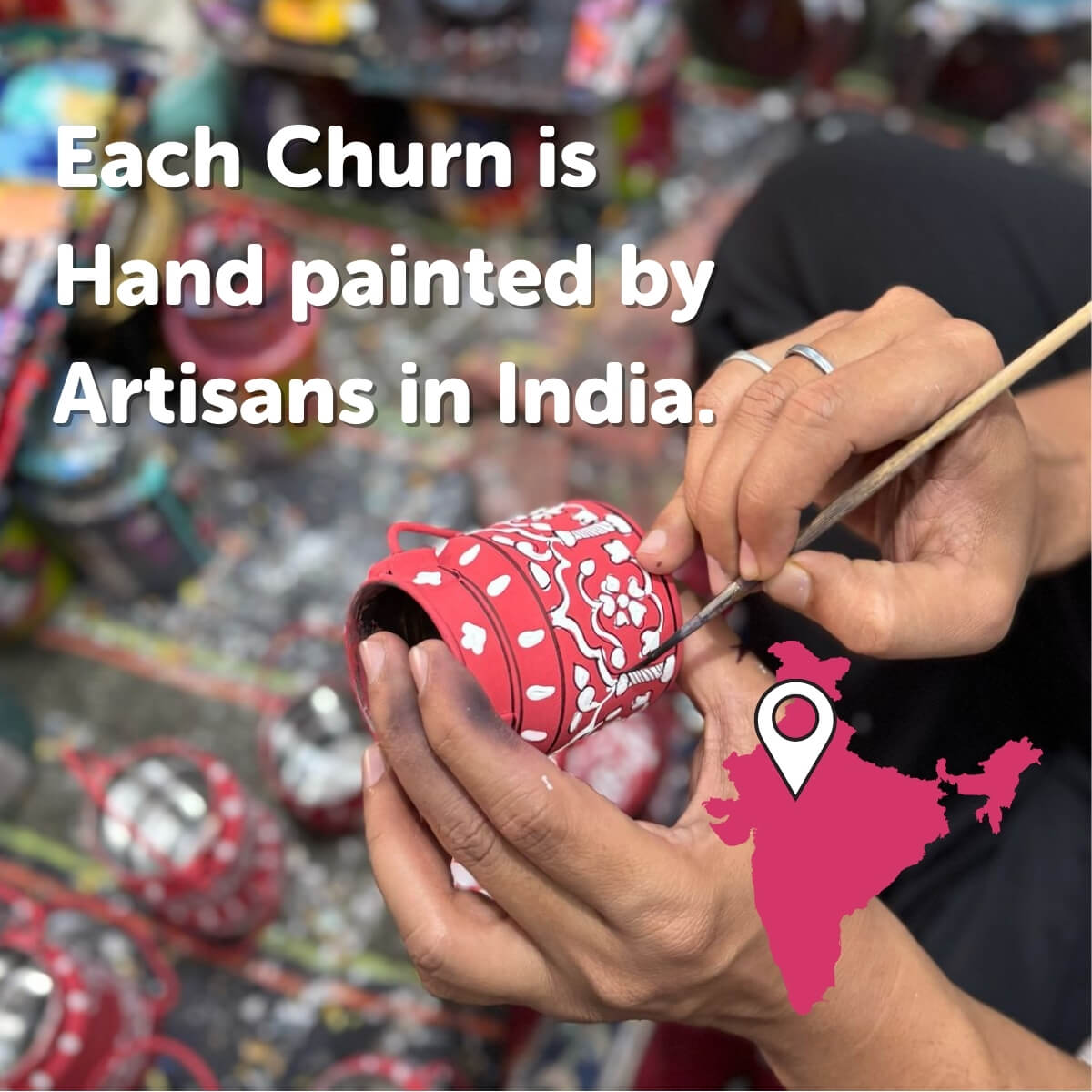 Person painting a red churn with floral patterns, surrounded by other churns and a map of India indicating artisanal origin.