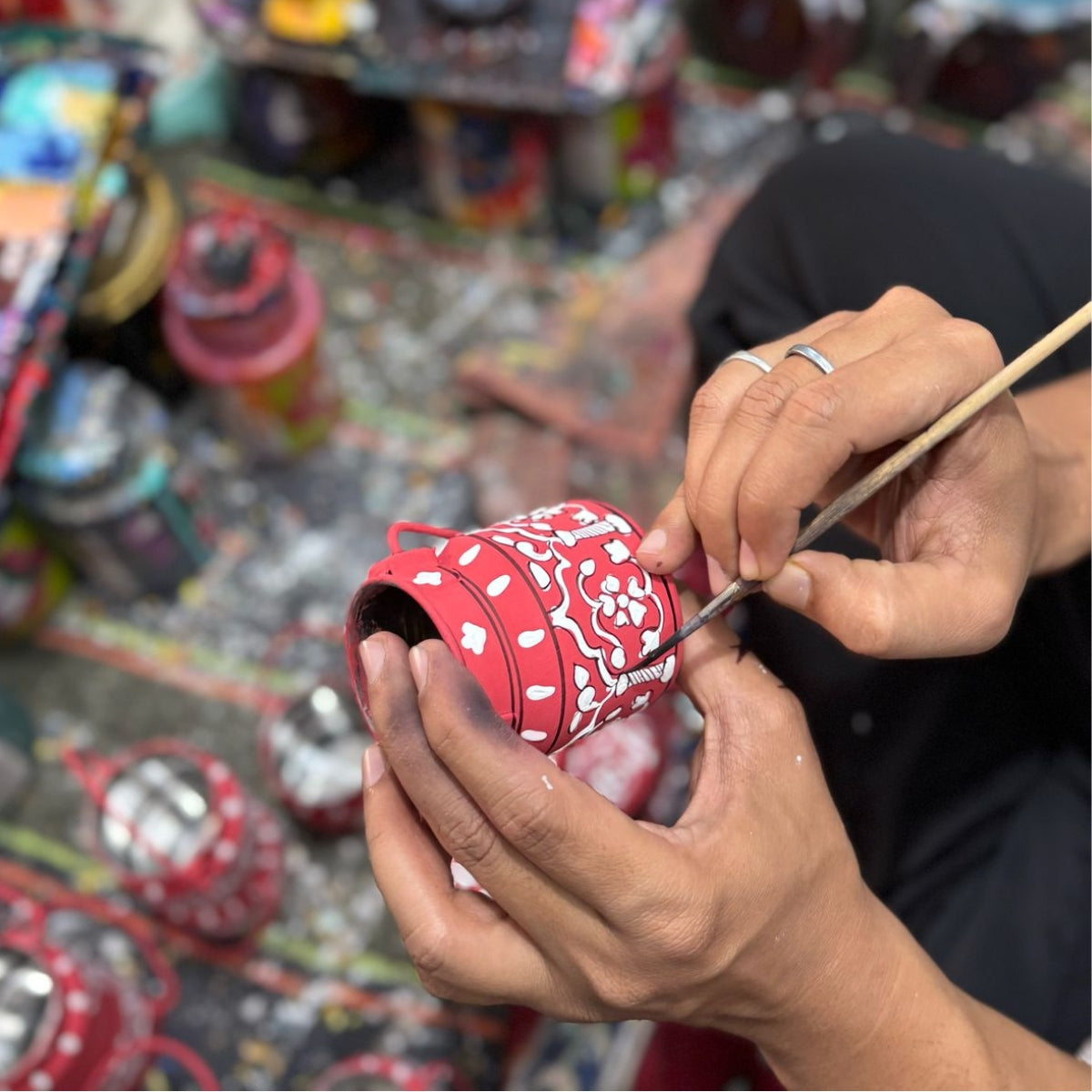 and Indian artisan hand paints a saabuni milk churn