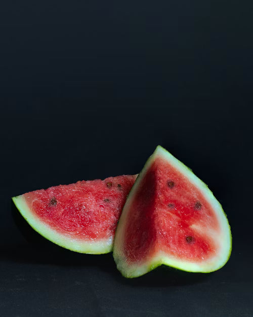 Two heart-shaped watermelon slices on a black background